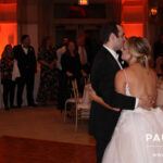 Golf course wedding DJ services provided for bride and groom, slow dancing in room with amber uplighting