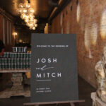 Sign that reads "Welcome To The Wedding Of Josh and Mitch 26 August 2022 Chicago, Illinois", next to a statue of an animal