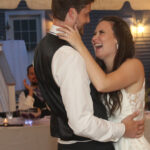 Bride and groom's first dance, groom's hands on the bride's hips, the bride's hands around the groom's neck, both laughing and cheerful