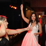 Photo of three women on the dance floor - one doing the sprinkler, one (the bride) with her hands in the air, and the third moving her hips. In the background, you can see DJ Tyler from Paul Michaels Events DJ Company playing the best music.