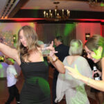 Two girls dancing with drinks in one hand and the other hand up in the air, on the dance floor of a wedding reception with the best Chicago area Wedding DJ, Paul Michaels Events