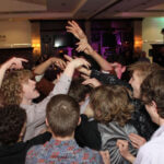 Photo of group of young people in the middle of the dance floor with their hands in the air, dancing to the Best Sweet 16 Chicago DJ at Ruffled Feathers Golf Club in Lemont, Illinois