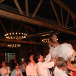 Bride getting lifted up by her crowd of guests at wedding event