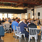 Group of people seated at tables for a meeting.