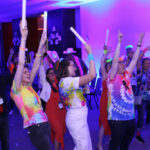 A group of people with hands and glow sticks in the air.