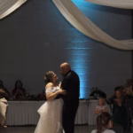 Bride & groom sharing first dance surrounded by loved ones